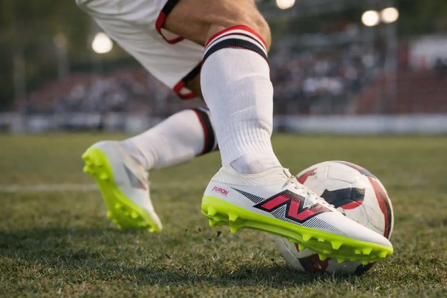 Chuteira New Balance Furon - controle e estabilidade no campo Atleta dominando a bola no gramado natural com chuteira New Balance Furon em foco, mostrando controle e estabilidade com ótimo custo-benefício